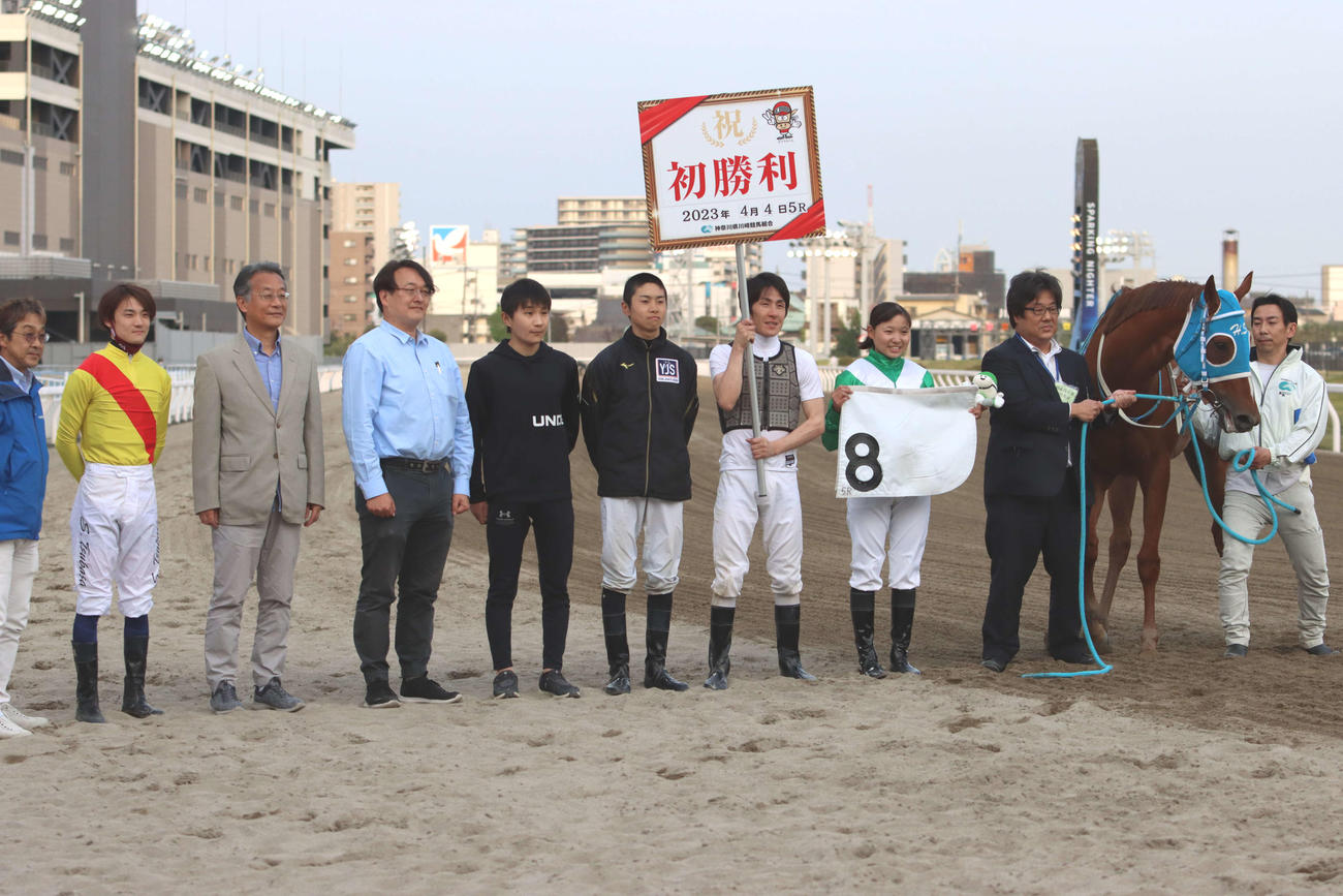 デビュー初勝利を挙げた小林美駒騎手（左から8人目）と記念撮影に納まる所属の鈴木伸尋師（同3人目）