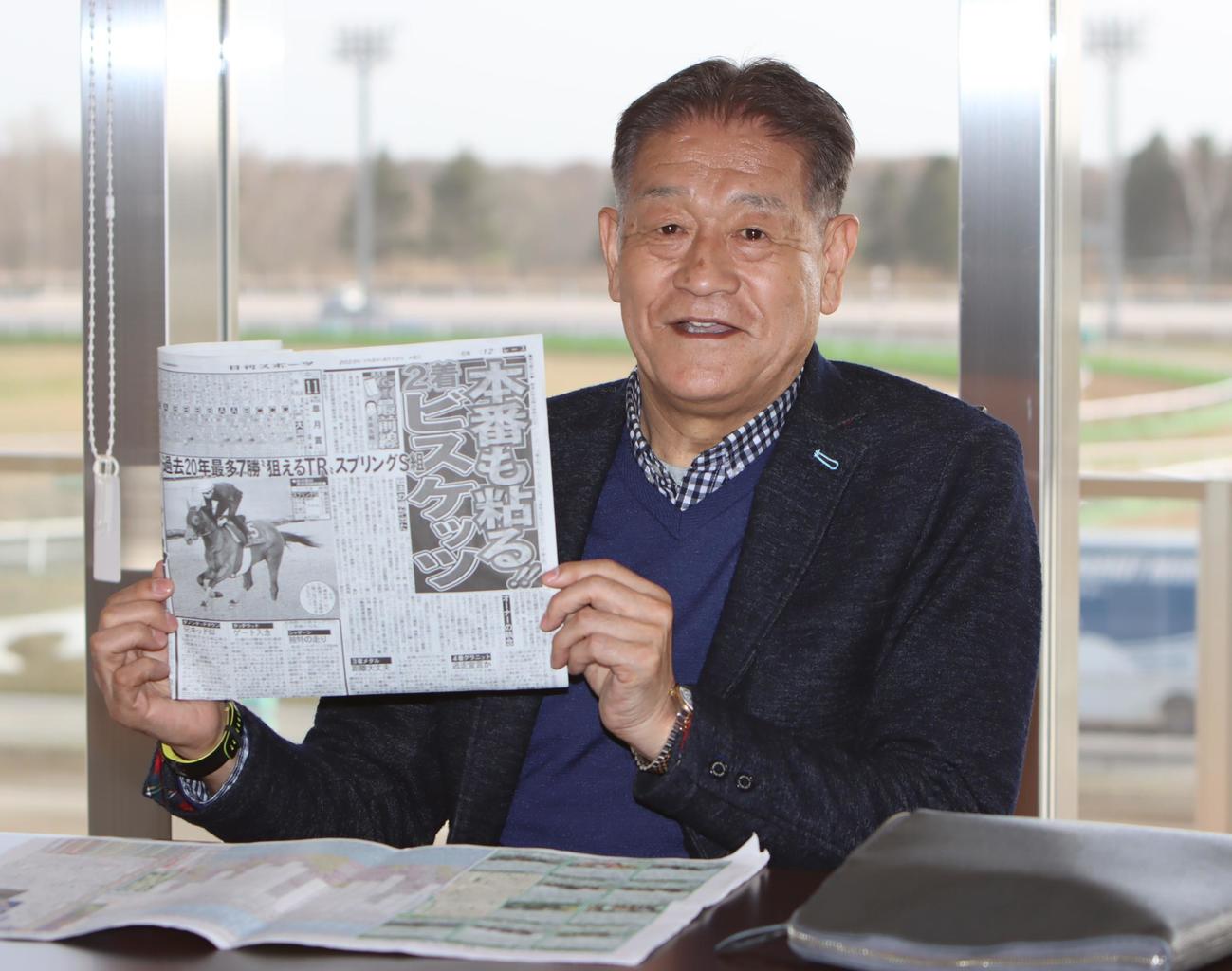 ホウオウビスケッツの記事を手にする岡田氏（撮影・奥村晶治）