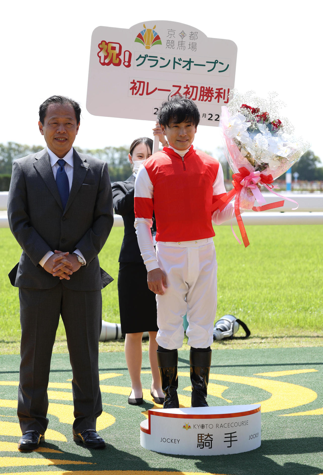 新装京都競馬場のオープニングレースを制し、セレモニーで花束を掲げる吉田隼騎手（右）（撮影・白石智彦）