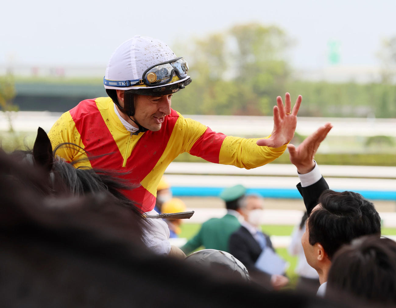 天皇賞・春を1着でゴールしたルメール騎手は関係者とタッチする（撮影・加藤哉）