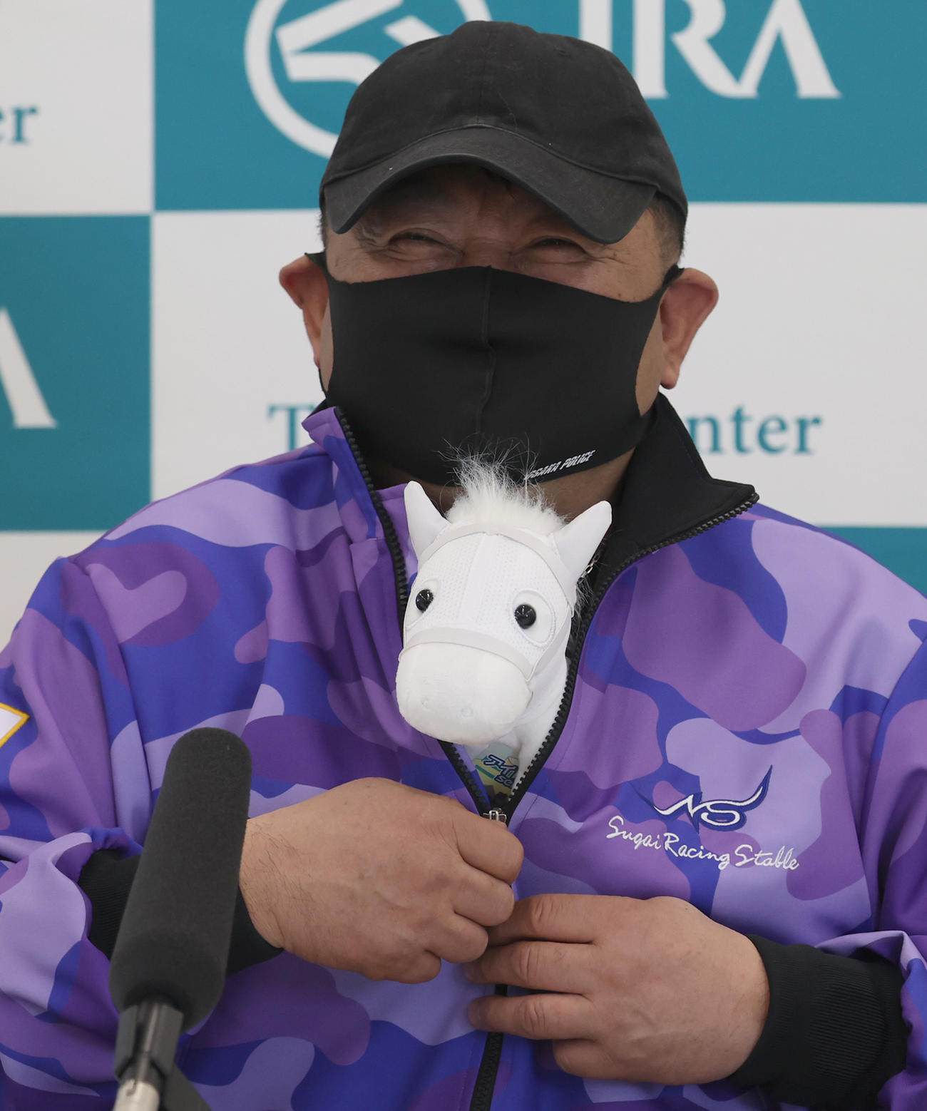 ソダシのぬいぐるみを懐に入れ笑顔で会見を行う須貝師