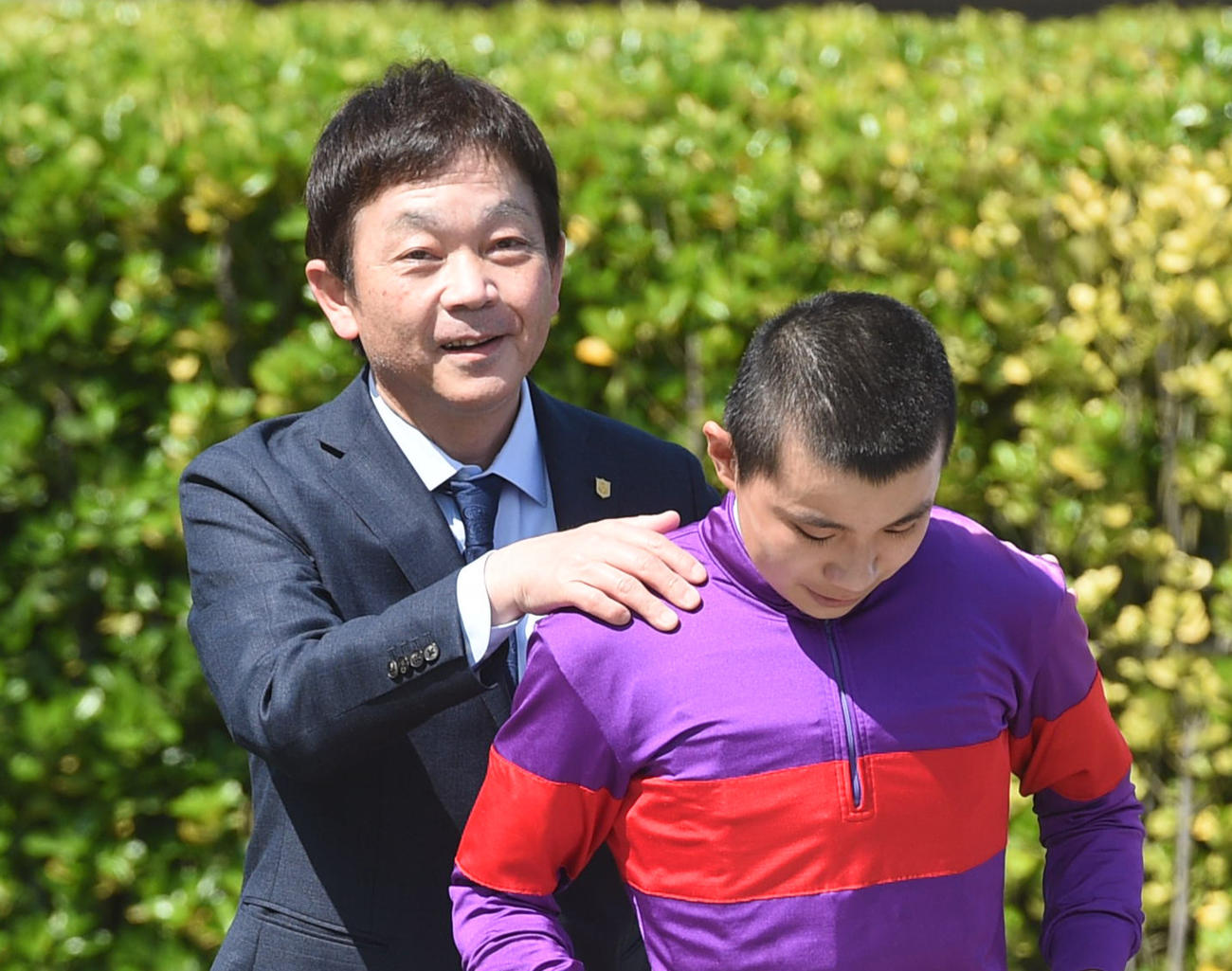 JRA初勝利を挙げた佐々木大輔騎手の肩をもんで祝福する菊川師（2022年4月撮影）