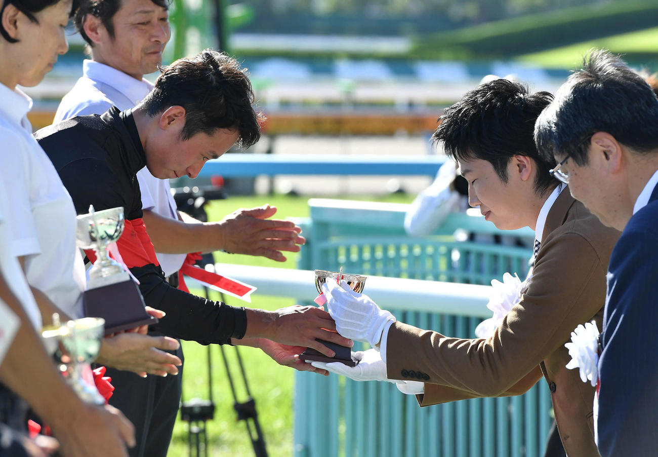 小倉11R・G3小倉2歳ステークス　アスクワンタイムで勝利し、表彰式で水谷隼氏（右）からカップを受け取る岩田望来騎手（撮影・岩下翔太）