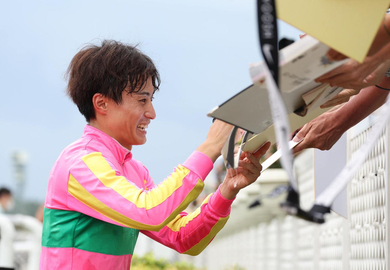 ウイナーズサークルに集まったファンにサインする富田騎手（撮影・白石智彦）