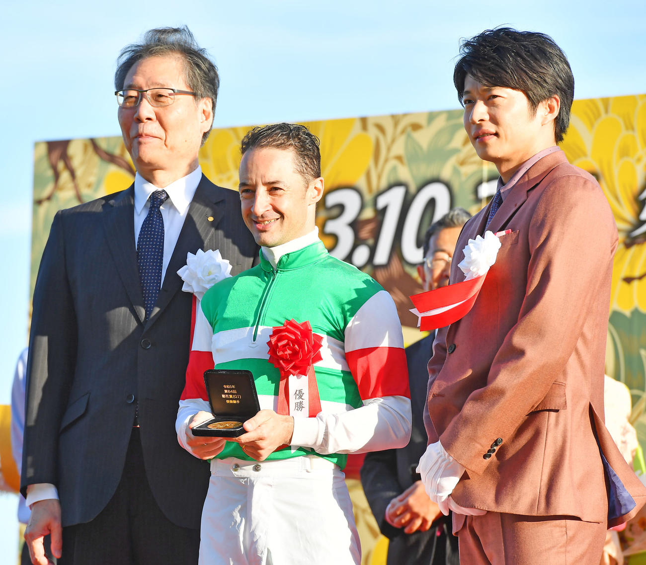 菊花賞を制し表彰を受けるC・ルメール騎手（中央）。右はプレゼンターの田中圭、左はJRA吉田理事長