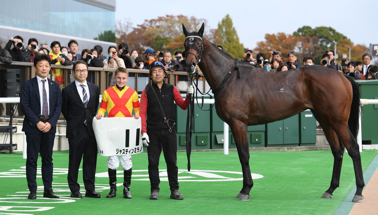 東京5R新馬戦を制したジャスティンミラノと友道調教師（左）、マーカンド騎手（左から3人目）