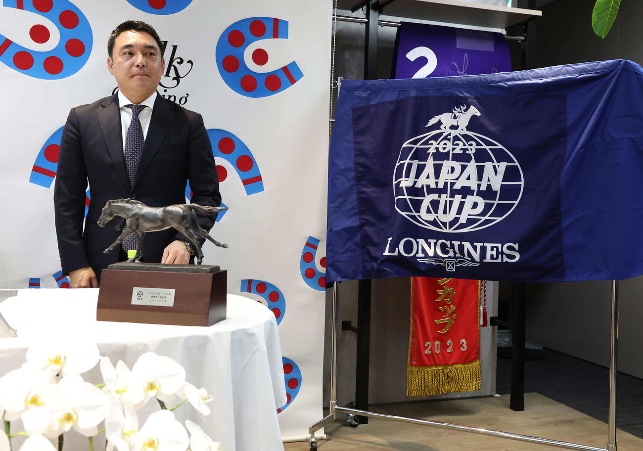 イクイノックスの引退、種牡馬入りを発表する米本代表。右はラストランとなったジャパンCのゼッケンやレイ