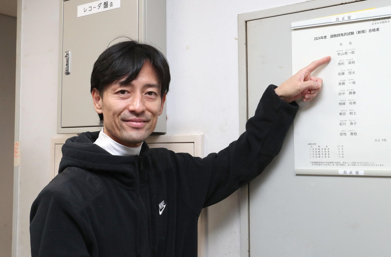 調教師試験に合格し自分の名前を指さす秋山真騎手（撮影・白石智彦）