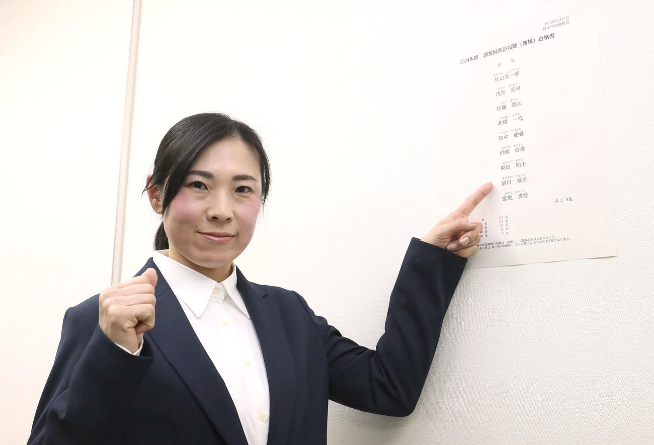 調教師試験合格者一覧から自分の名前を指さしガッツポーズする前川恭子助手（撮影・白石智彦）