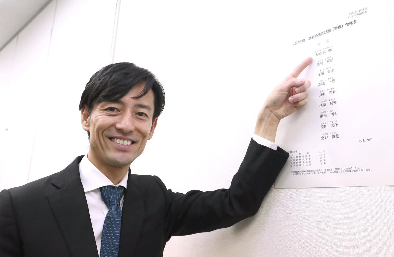 調教師試験合格者一覧から自分の名前を笑顔で指さす秋山真騎手（撮影・白石智彦）