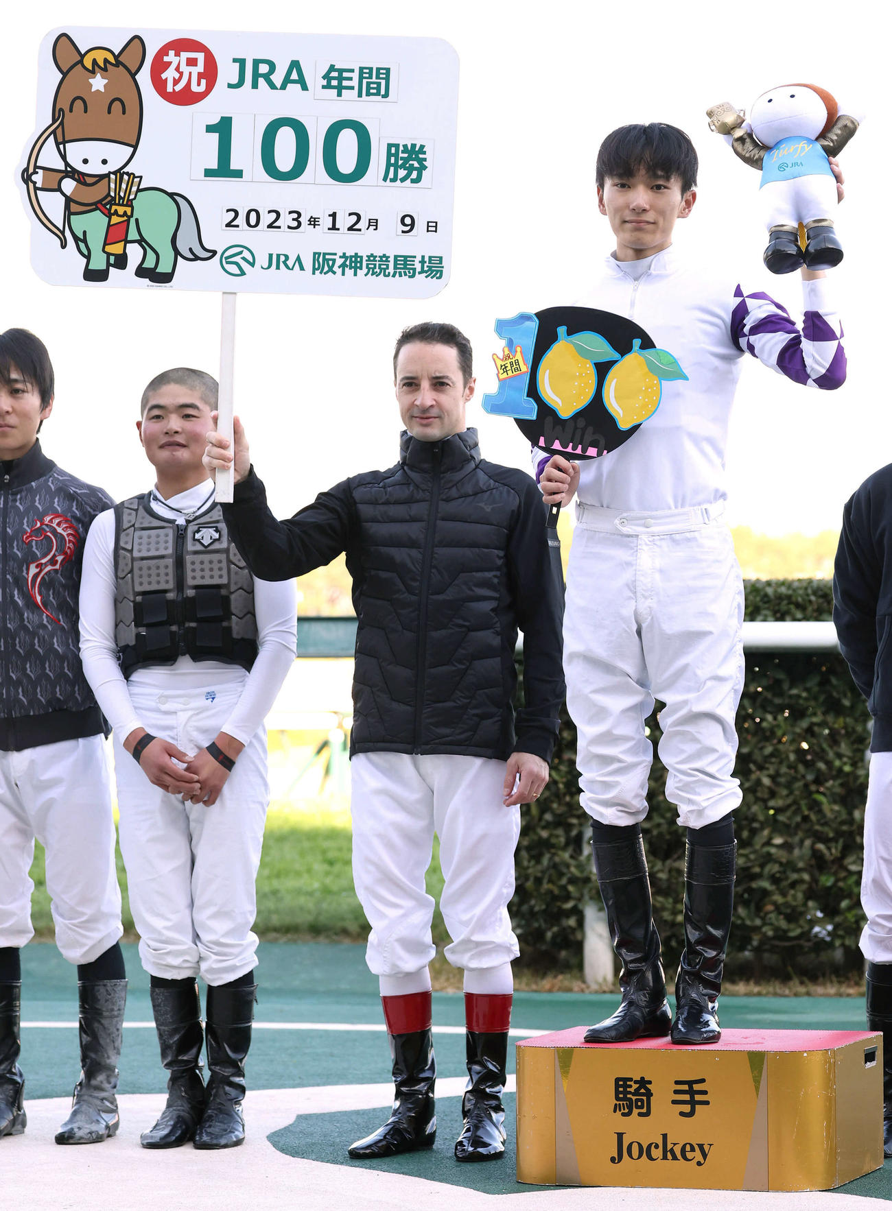 JRA年間100勝を達成し写真に納まる坂井騎手（右）。ボードを持つC・ルメール騎手（撮影・白石智彦）