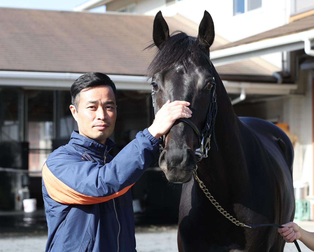 ジャスティンパレスの顔をなでる杉山晴師（2023年12月撮影）