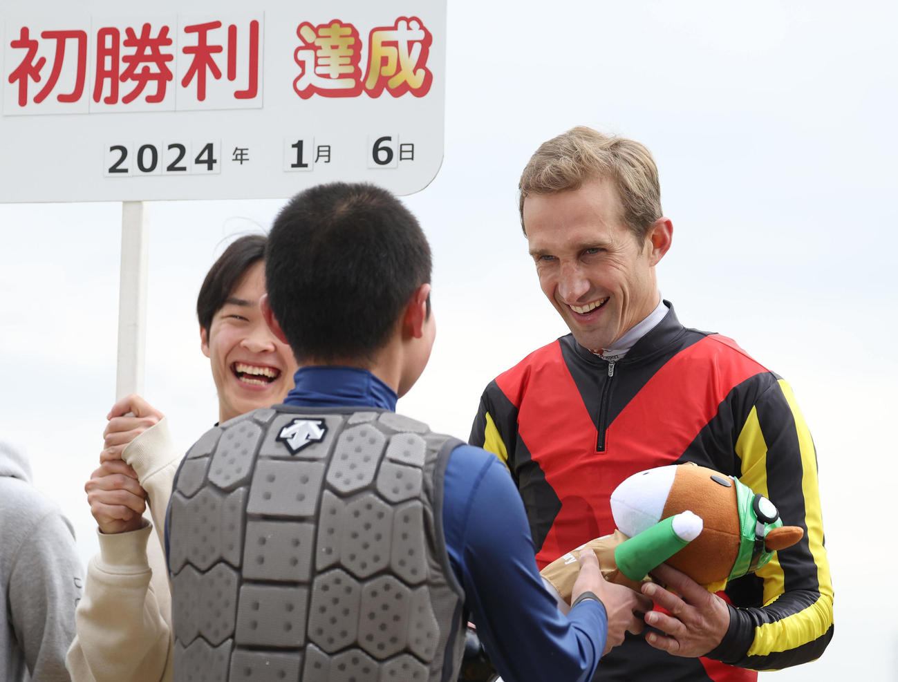 プレゼンターの田口騎手（手前）からJRA初勝利のお祝いのターフィー人形を受け取るA・ルメートル騎手（撮影・白石智彦）
