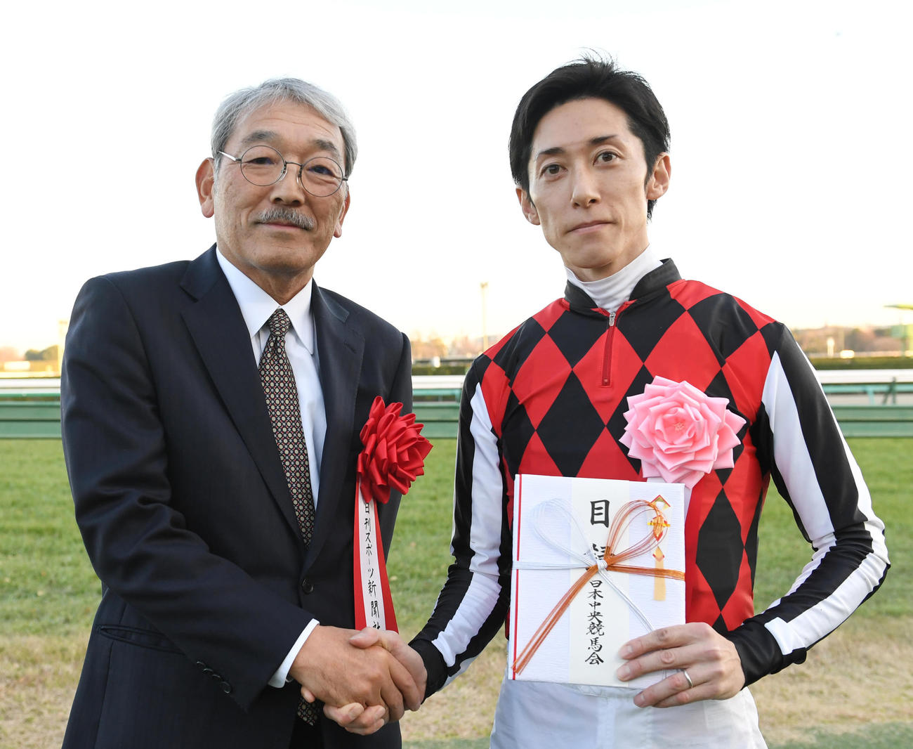 中山金杯を制した津村騎手（右）は日刊スポーツ新聞社の高田社長と握手する（撮影・柴田隆二）