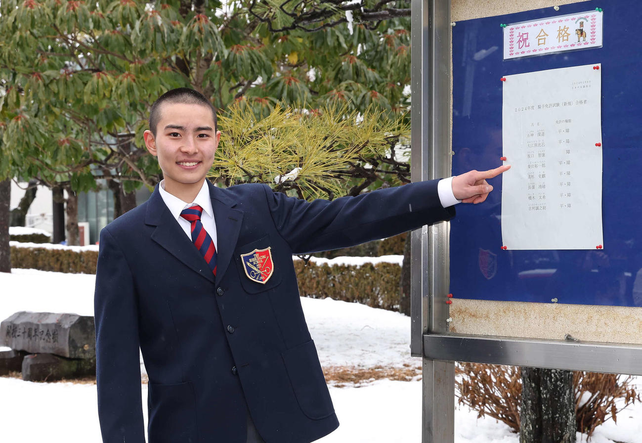 合格者名簿の前で写真に納まる柴田裕一郎（撮影・丹羽敏通）
