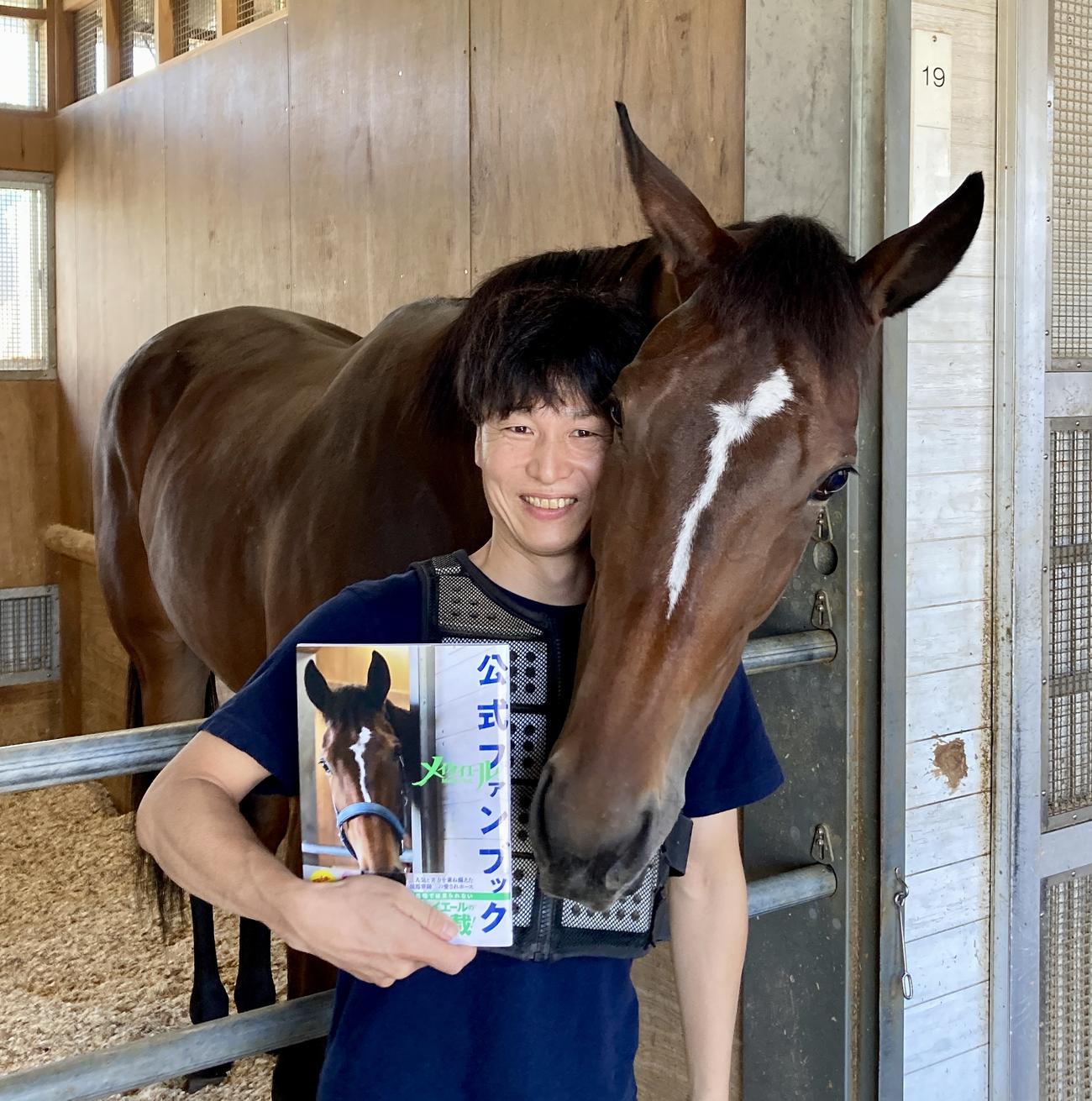 公式ファンブックを手にした吉田助手に顔を寄せるメイケイエール（2023年9月撮影）