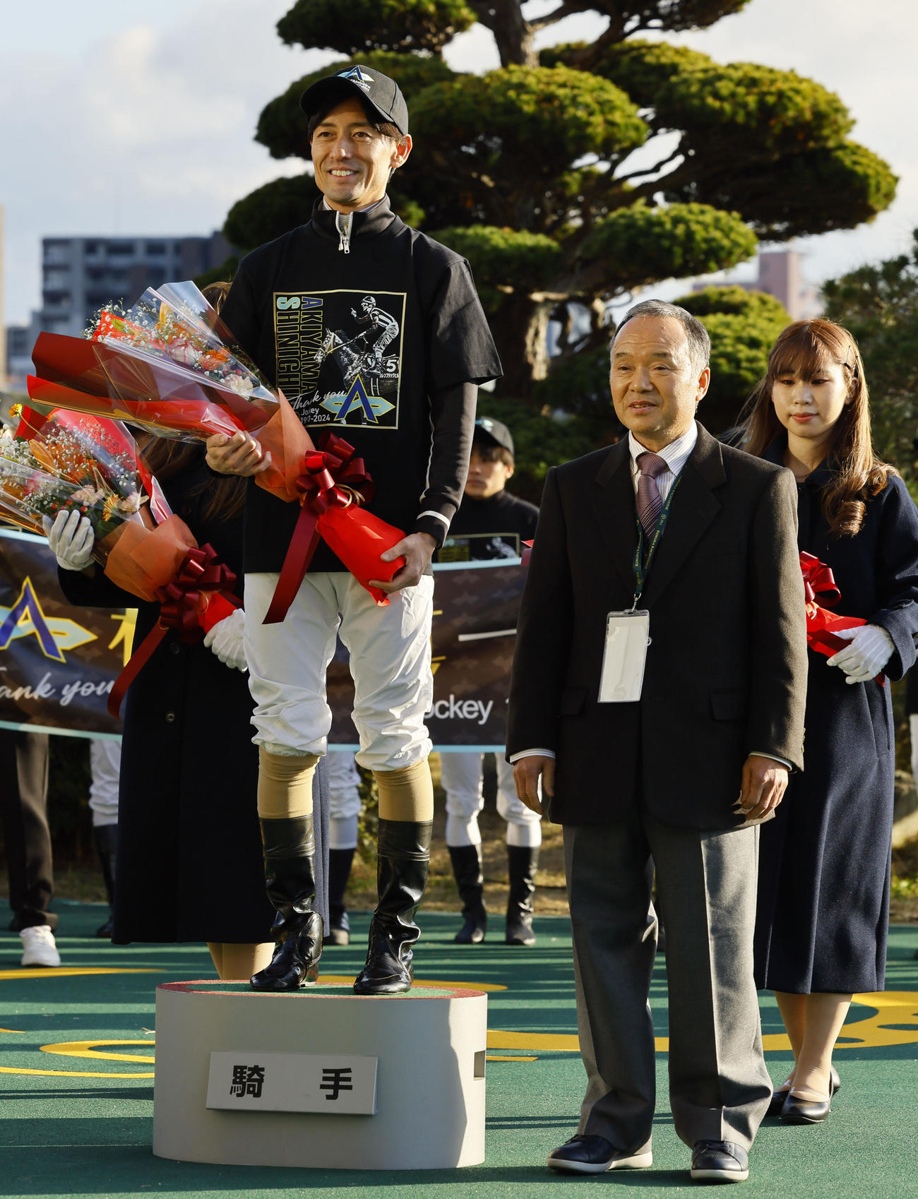 引退式で父忠一さん（右）から花束を贈られ、記念写真に納まる秋山真騎手（撮影・藤尾明華）