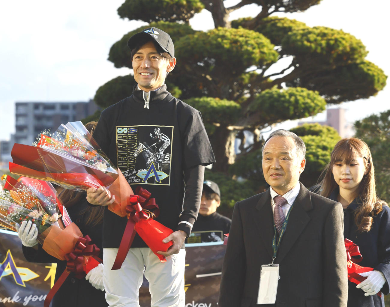 引退式で父忠一さん（右）から花束を贈られ、記念写真に納まる秋山真騎手（撮影・藤尾明華）