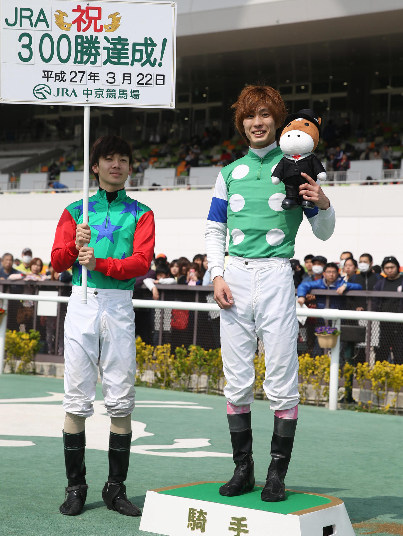 15年、JRA通算300勝を達成した藤岡康太騎手（右）。左はボードを持つ松山騎手