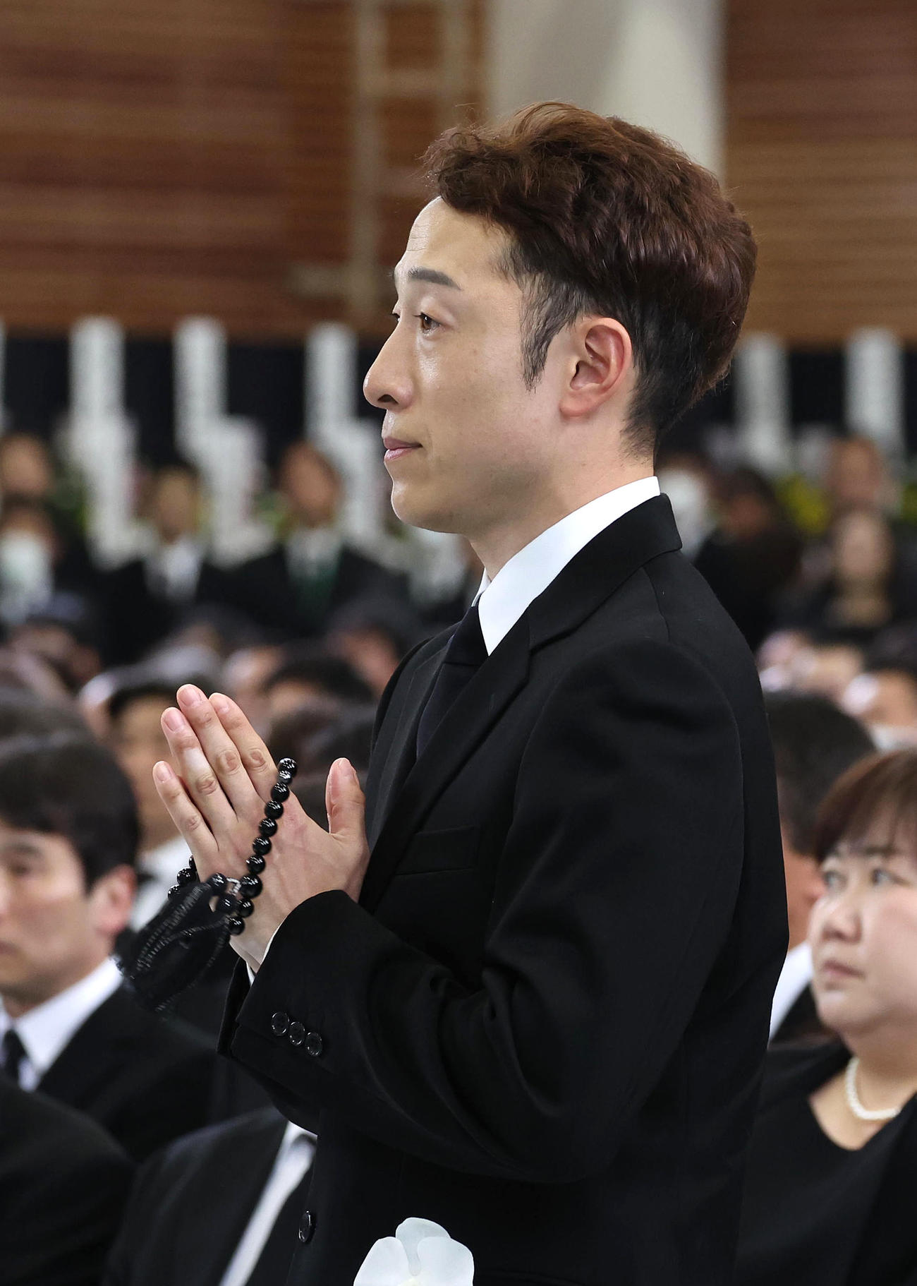 故藤岡康騎手の合同葬で焼香台の前で手を合わせ祭壇を見つめる兄の藤岡佑騎手（撮影・白石智彦）