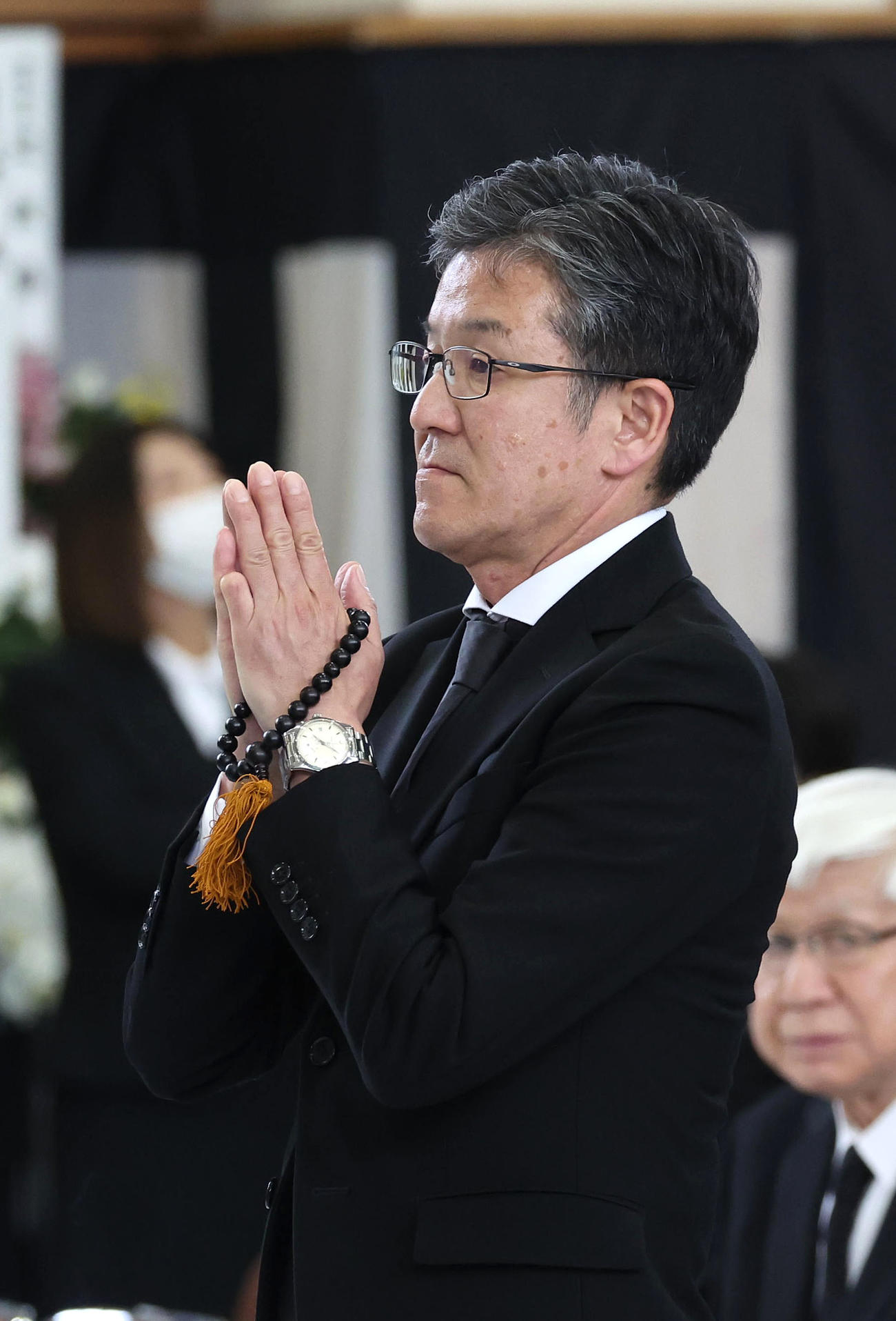 故藤岡康騎手の合同葬で焼香台の前で手を合わせ祭壇を見つめる中竹師（撮影・白石智彦）