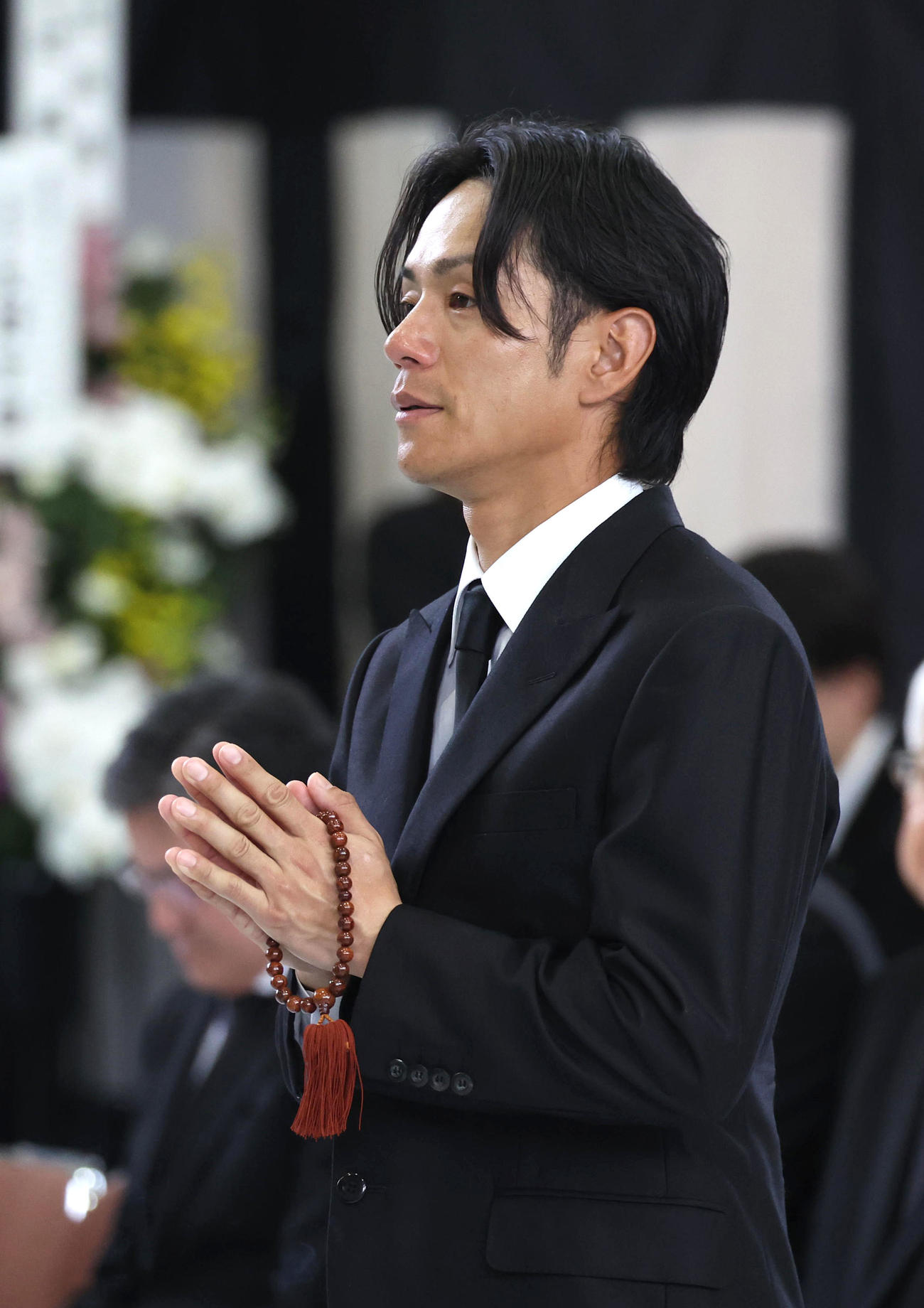 故藤岡康騎手の合同葬で焼香台の前で手を合わせ祭壇を見つめる浜中騎手（撮影・白石智彦）