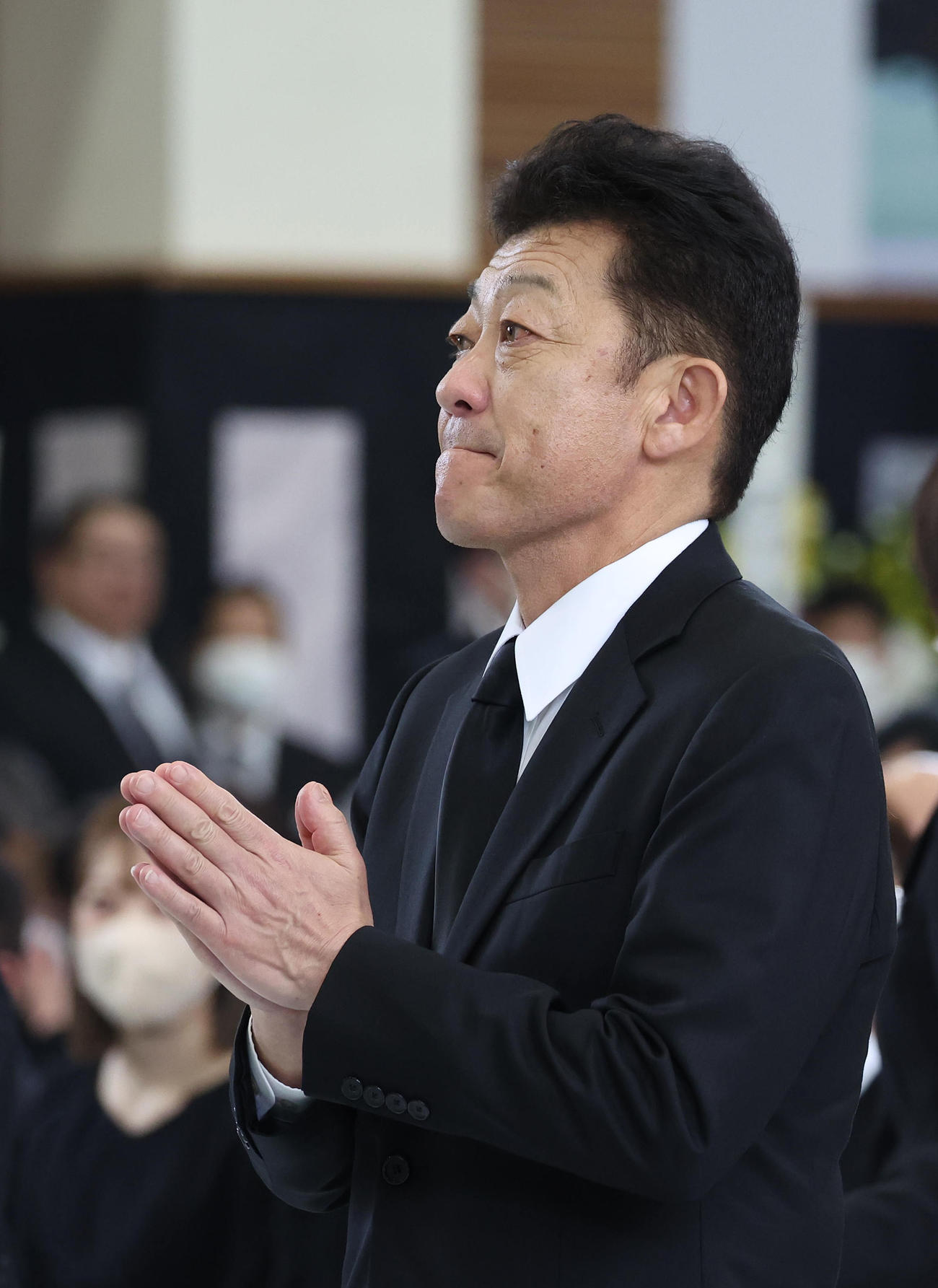 故藤岡康騎手の合同葬で焼香台の前で手を合わせ祭壇を見つめる友道師（撮影・白石智彦）
