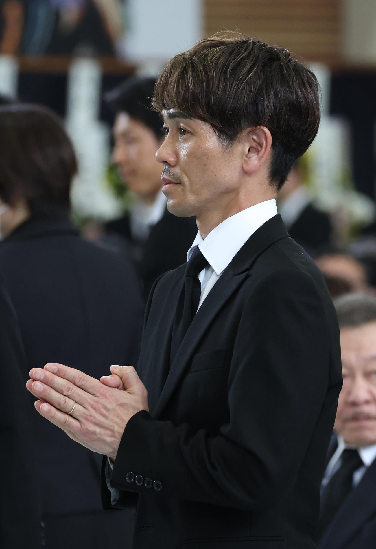 故藤岡康騎手の合同葬で焼香台の前で手を合わせ祭壇を見つめる戸崎騎手（撮影・白石智彦）