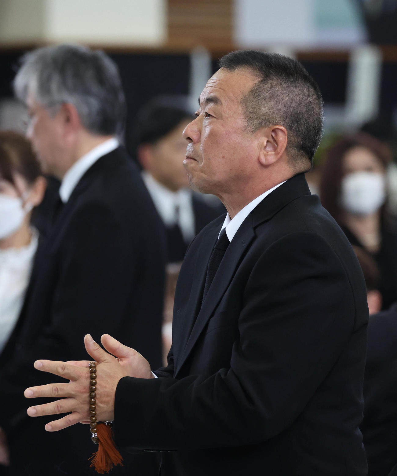 故藤岡康騎手の合同葬で焼香台の前で手を合わせ祭壇を見つめる師匠の宮師（撮影・白石智彦）