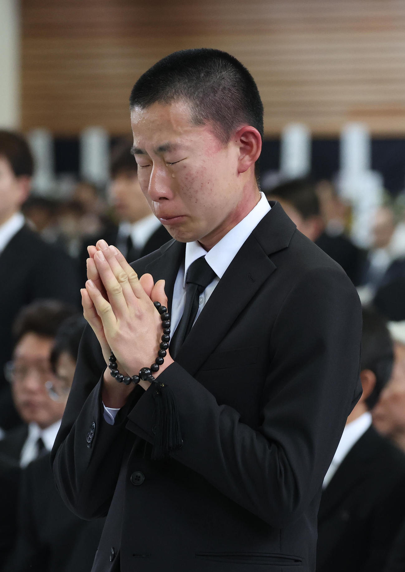 故藤岡康騎手の合同葬で焼香台の前で涙を流しながら合掌するルーキーの高杉騎手（撮影・白石智彦）