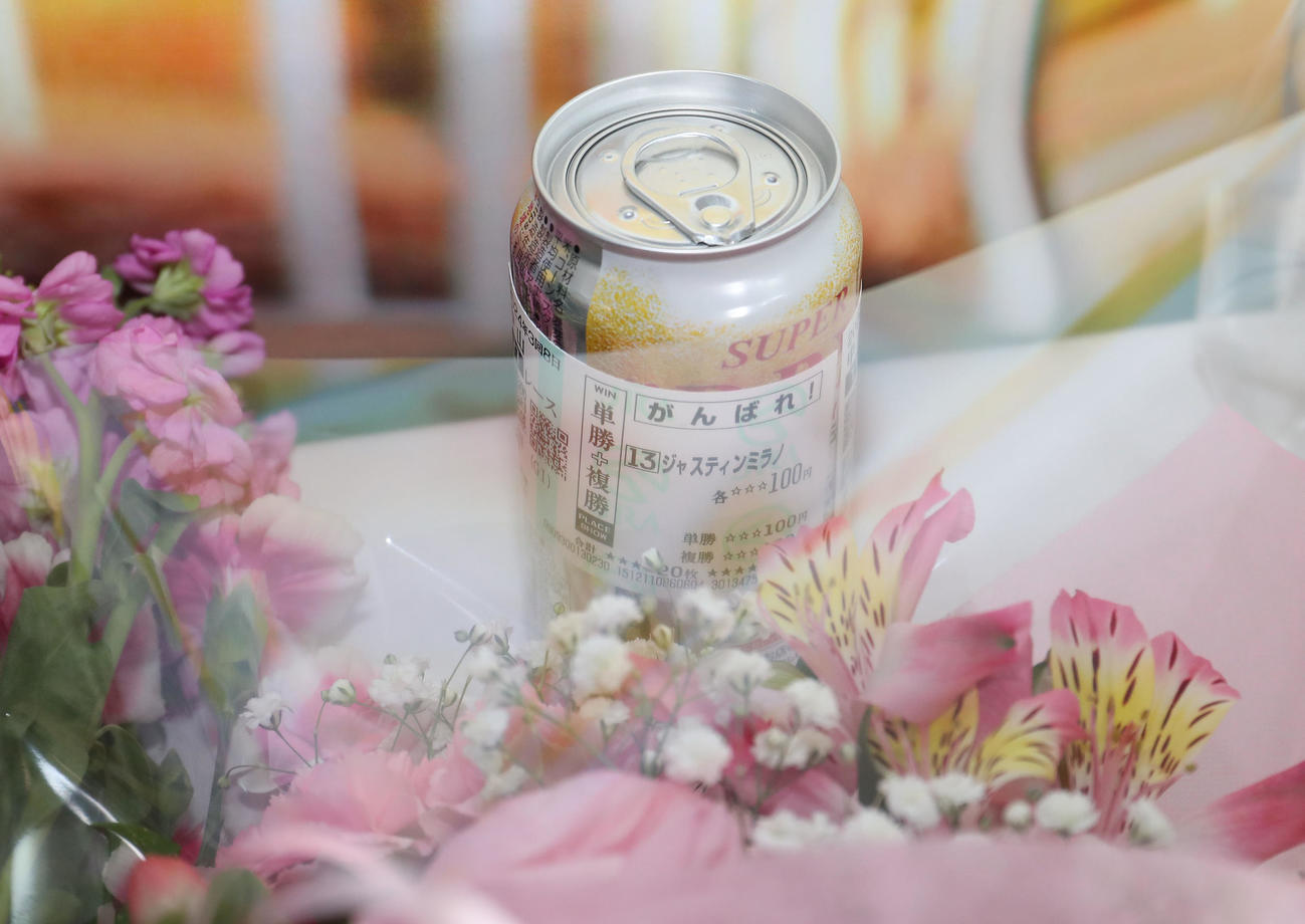 ファン向けの献花台にお供えされたジャスティンミラノの馬券に包まれたビール（撮影・白石智彦）