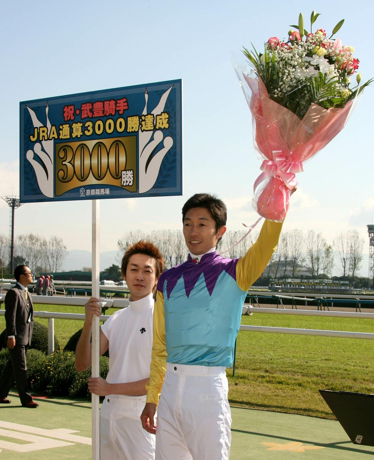 07年11月、3000勝を達成しファンの声援に花束を揚げて応える武豊騎手。左は弟の幸四郎騎手