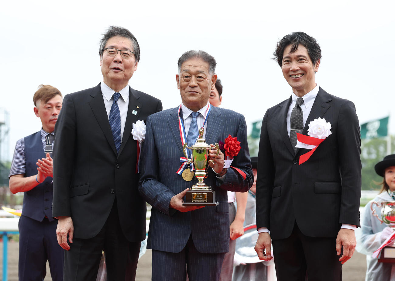 記念写真に納まる左から、吉田正義JRA理事長、岡田牧雄オーナー、プレゼンターの佐々木蔵之介