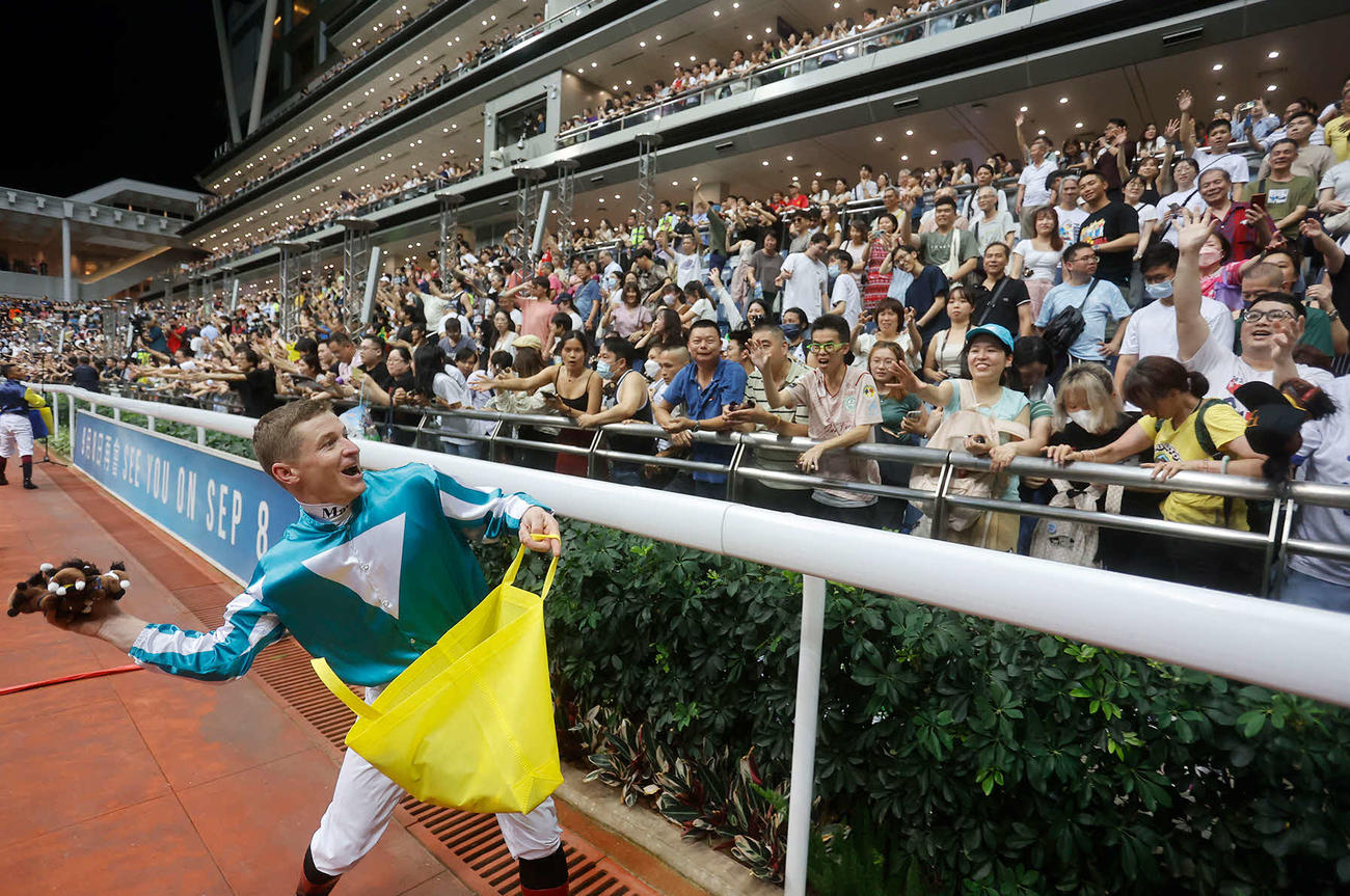 ぬいぐるみを投げ込むロマンチックウォリアーのマクドナルド騎手（（C）The Hong Kong Jockey Club）