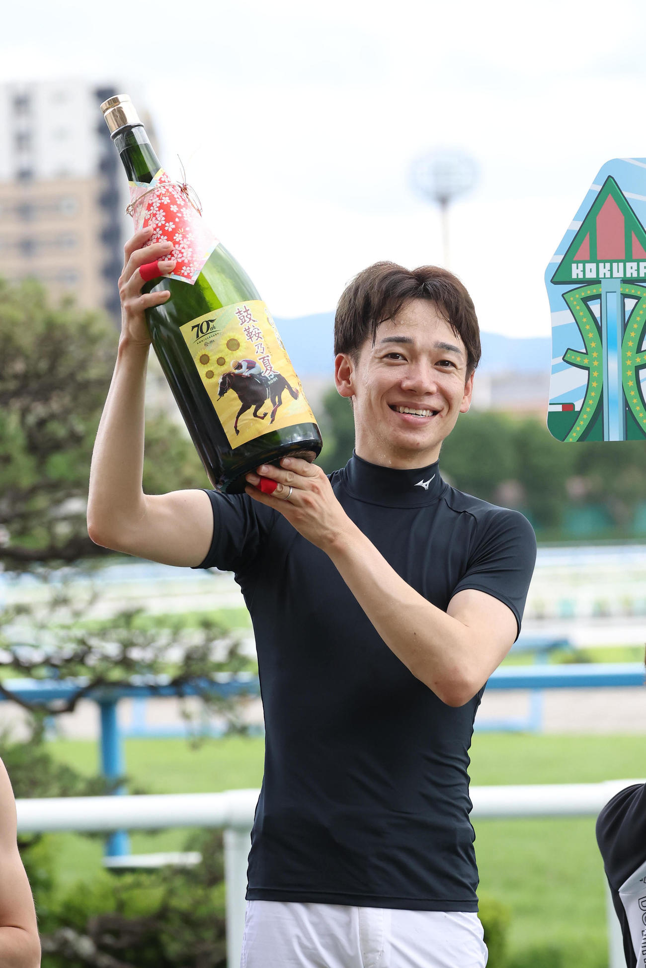 夏の小倉開催のリーディングジョッキーに輝きオリジナル焼酎を掲げる松山騎手（撮影・白石智彦）