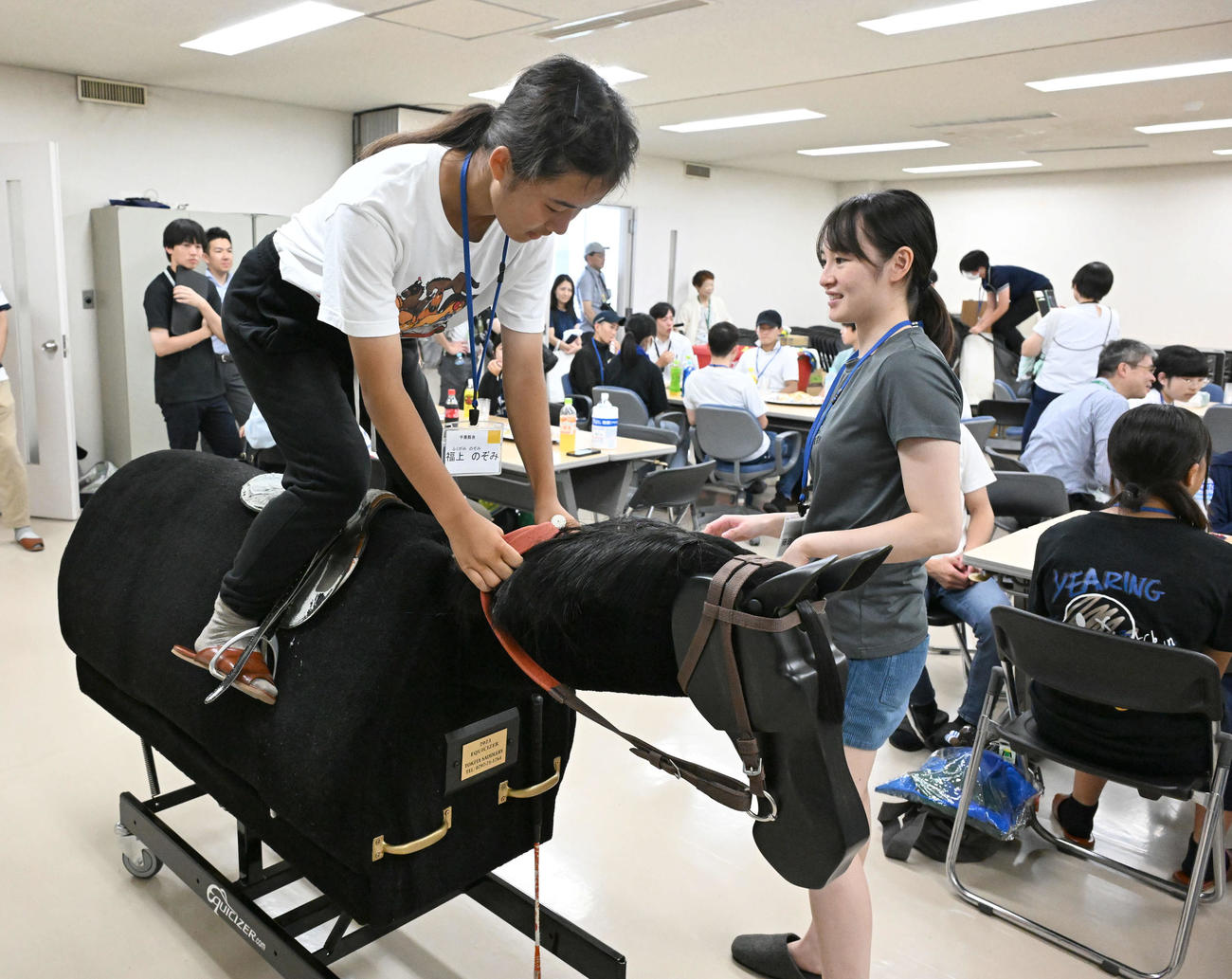 藤田騎手（右）の指導で木馬にまたがる参加した中学生（撮影・千葉一成）