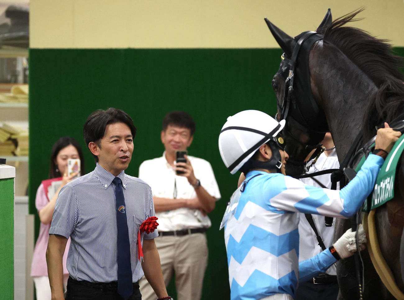 引き揚げてきたドロップオブライトと幸騎手（右）を出迎える福永師（撮影・白石智彦）