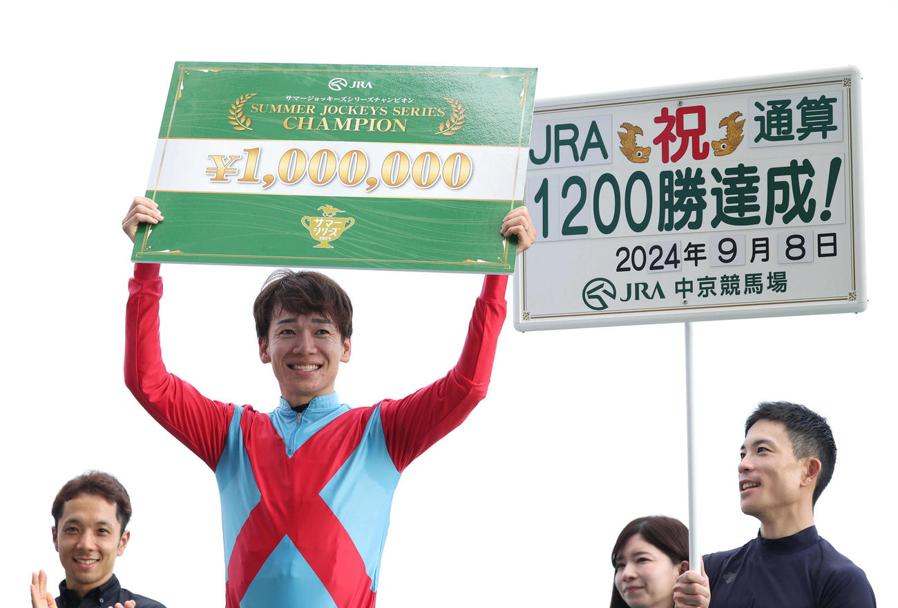 JRA通算1200勝＆サマージョッキーズシリーズチャンピオンの松山騎手はボードを掲げる