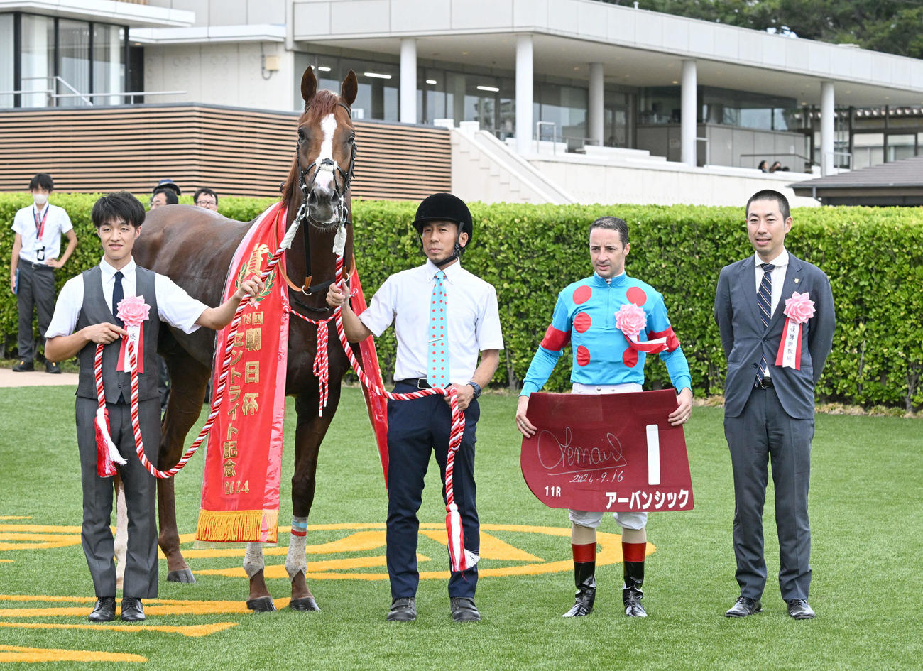 朝日杯セントライト記念を制したアーバンシックの口取りをするルメール騎手と武井師（右端）