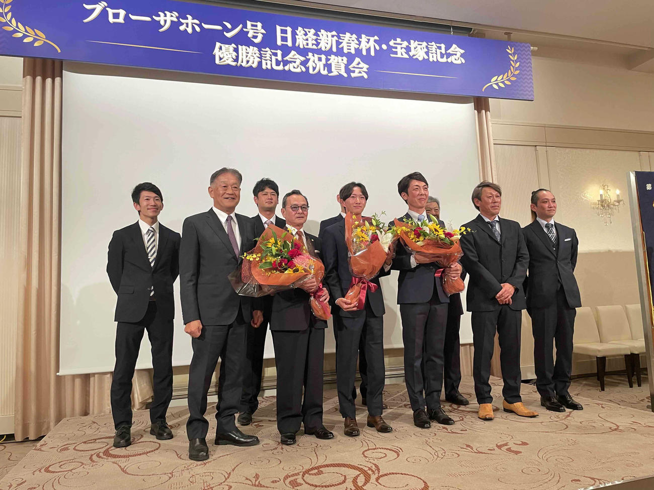 記念写真に収まる岡田牧雄代表、中野栄二元調教師、菅原明良騎手、吉岡辰弥調教師ら関係者