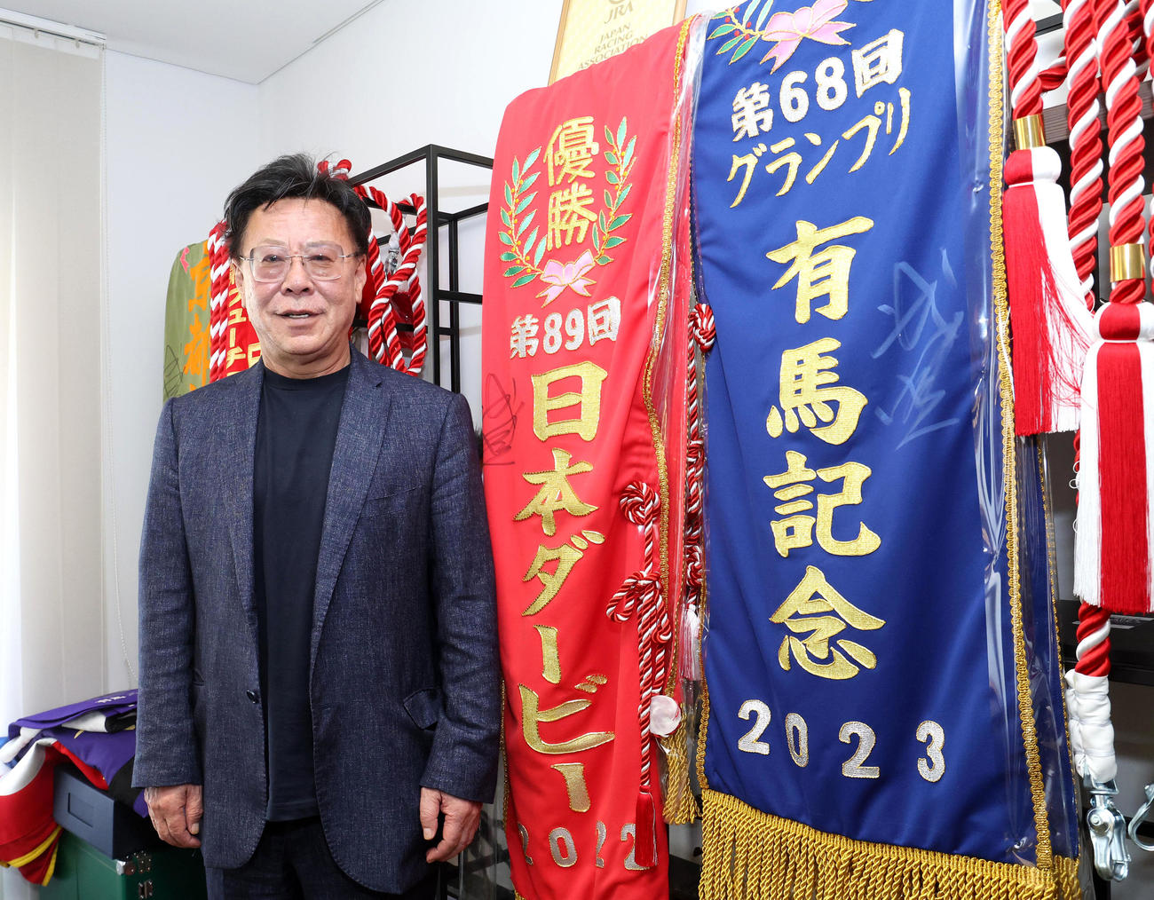 優勝レイをバックに笑顔を見せる松島オーナー（撮影・白石智彦）