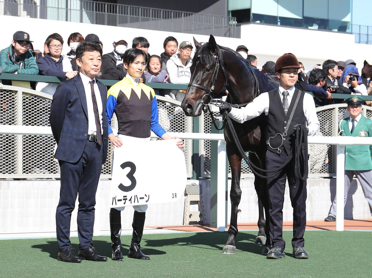 京都3R、2歳未勝利を勝ち上がったパーティハーンと口取りに並ぶ坂井騎手（中央）（撮影・白石智彦）