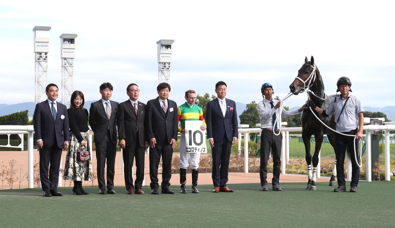 京都5R新馬戦を制したエコロディノスと口取りに並ぶムーア騎手（右から4人目）（撮影・白石智彦）