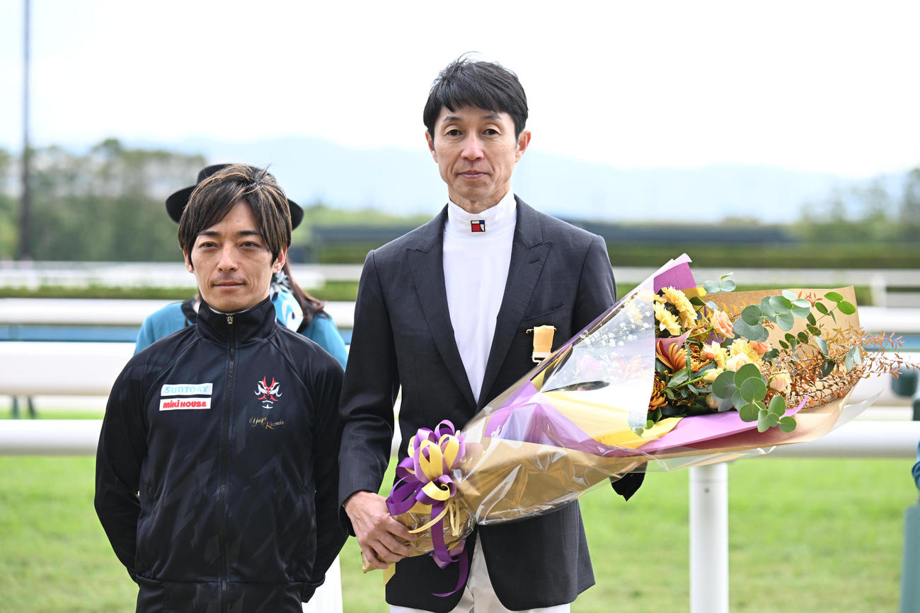 黄綬褒章を受賞し、川田騎手（左）から花束を贈られた武豊騎手（撮影・和賀正仁）
