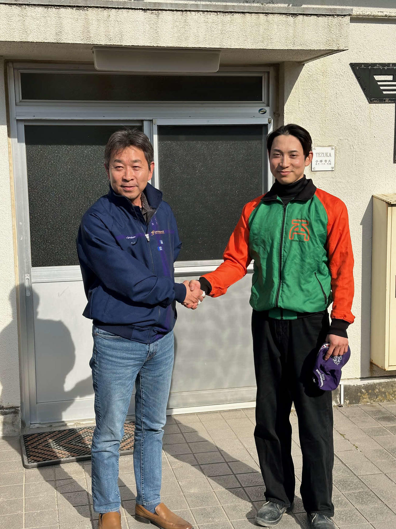 父の手塚貴久師（左）と握手を交わす手塚貴徳助手