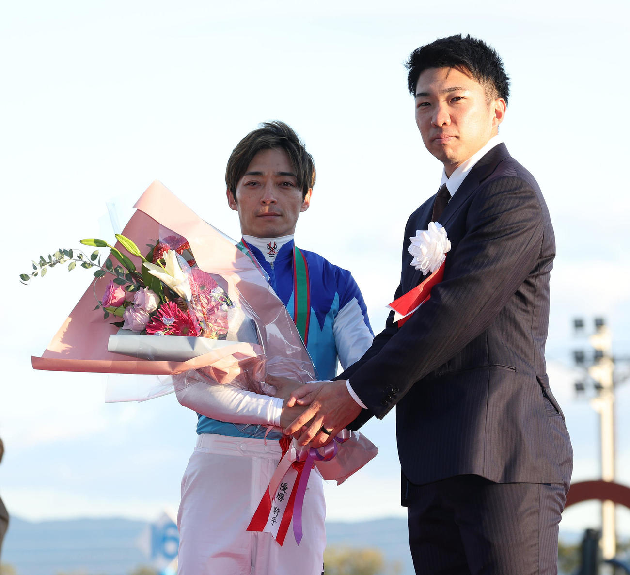 握手をする朝日杯FSを制した川田騎手（左）とプレゼンターの阪神石井（撮影・白石智彦）