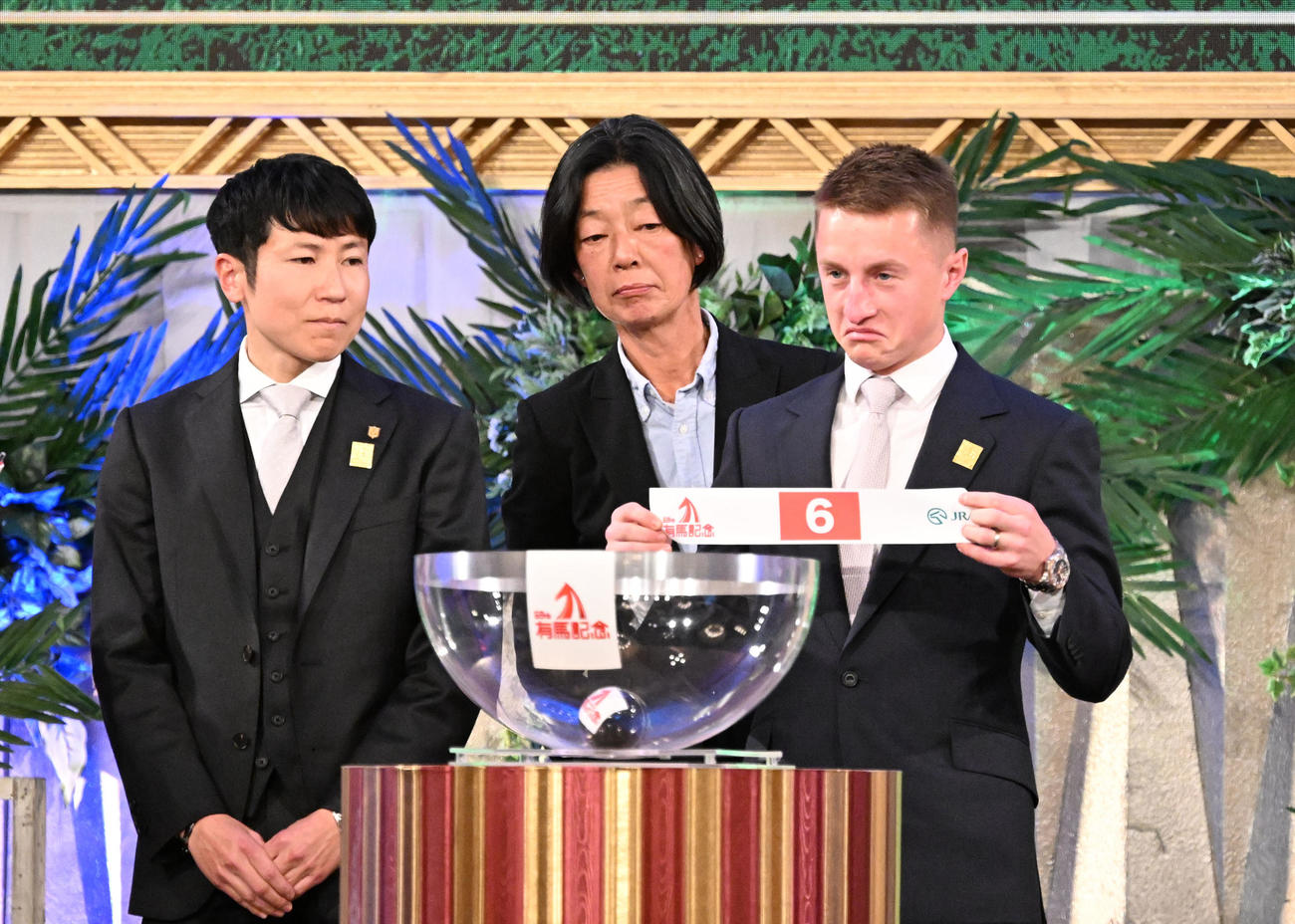 有馬記念の枠順公開抽選会でローシャムパークの枠順6番を引いた、マーカンド騎手。左は田中博師