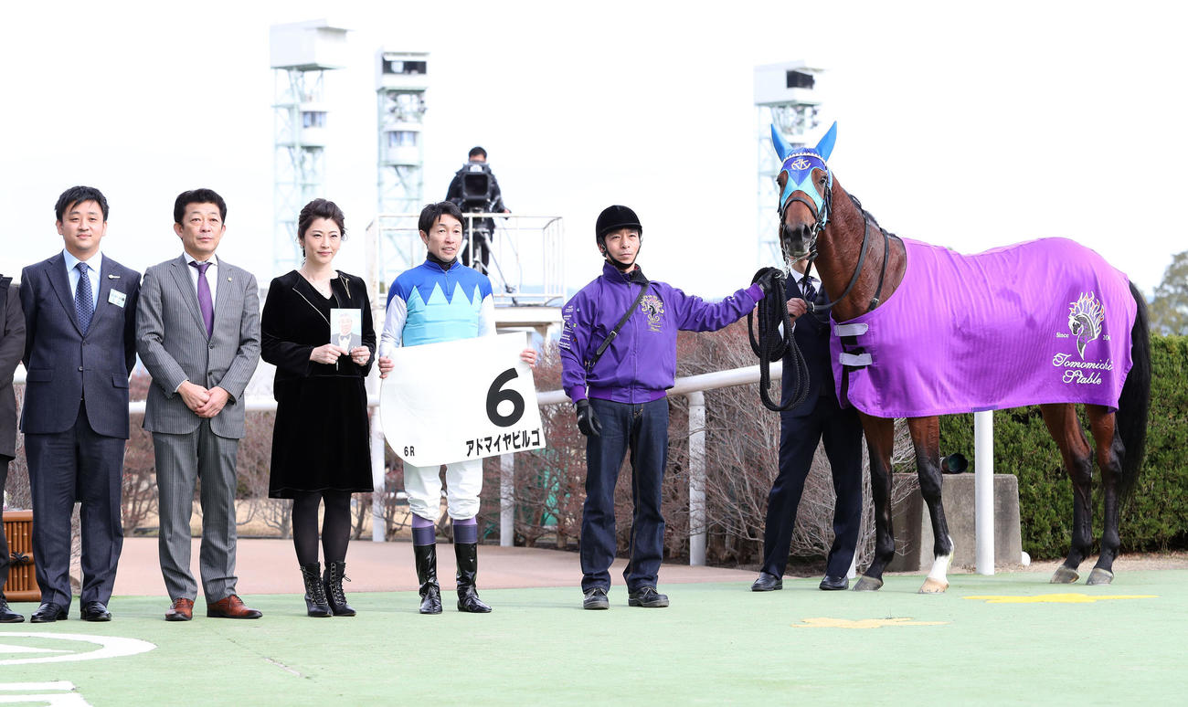 アドマイヤビルゴで新馬戦を快勝して口取りに並ぶ武豊騎手と近藤利一氏の遺影を手にする旬子夫人