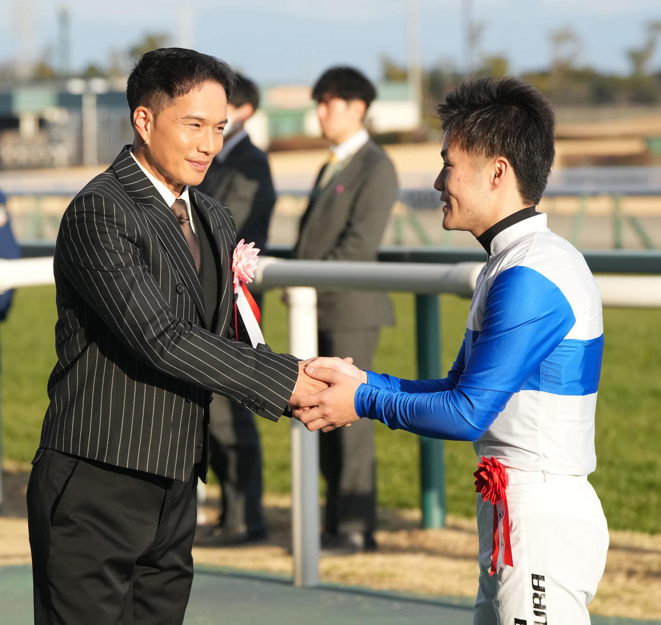 日経新春杯をロードデルレイで制した西村淳騎手（右）はプレゼンターの市原隼人と握手をかわす