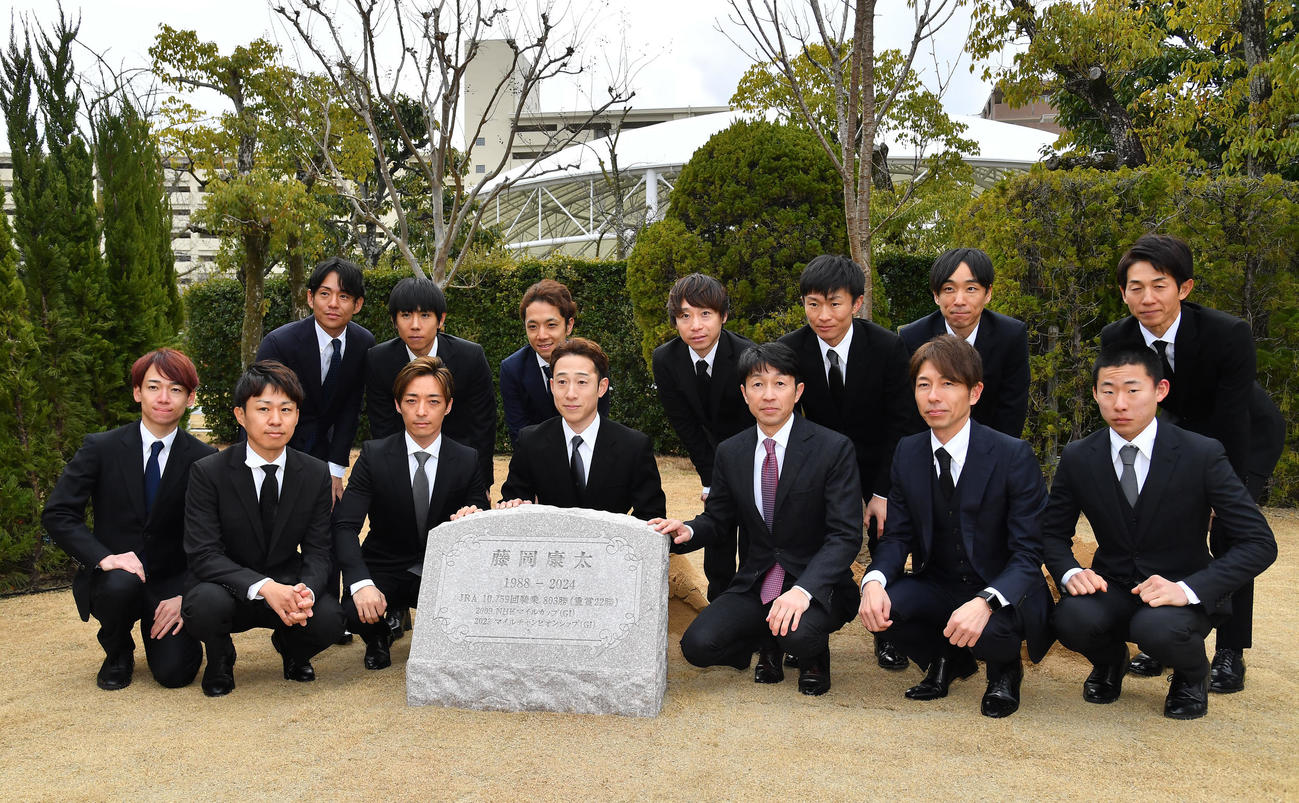 故・藤岡康太騎手追悼植樹式で石碑とともに写真に納まる式に出席した騎手たち（撮影・清水貴仁）